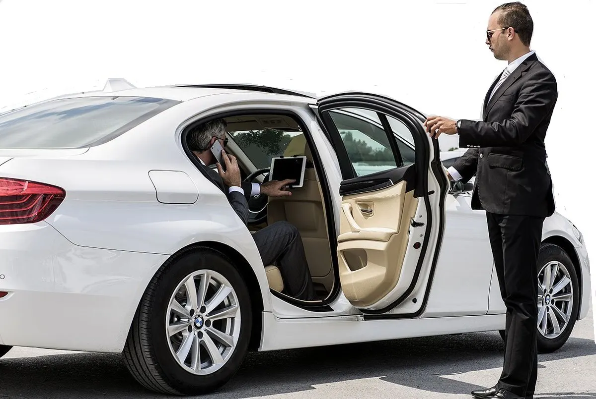 cambridge airport limo-A man stepping out of a white limousine as a chauffeur in a black suit opens the door to welcome him,representing premium and professional cambridge limo service.