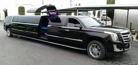 Toronto To Niagara Winery Tours-A sleek black stretch limousine with gull-wing doors open, parked on a paved area. Interior neon lights create a luxurious, modern atmosphere.
