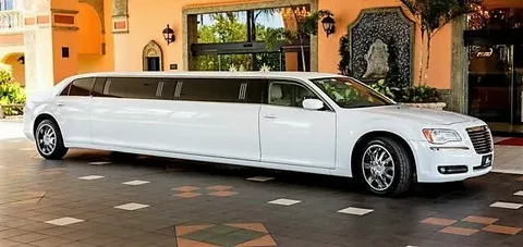 Barrie to Pearson Airport Limo-A sleek white limousine parked at an elegant entrance with arches and greenery. The scene exudes luxury and sophistication under bright daylight.