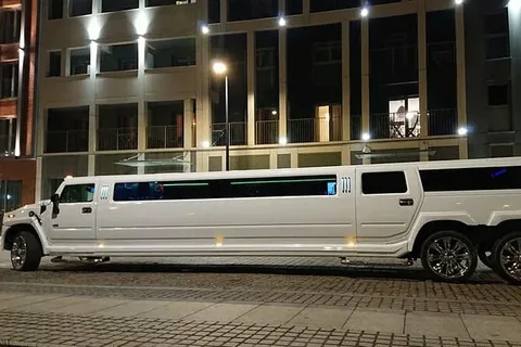 richmond hill limo service-A sleek black limousine parked on a paved road beside a tranquil lake lined with lush green trees, conveying luxury and elegance under a clear sky.