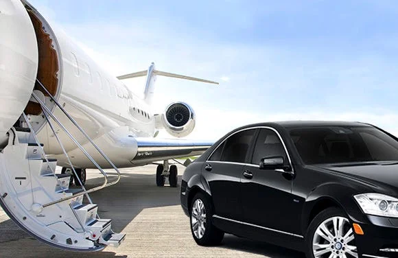 markham limo service-A sleek black car is parked on an airport runway beside a white private jet with an open staircase, under a clear blue sky. The scene suggests luxury and travel.
