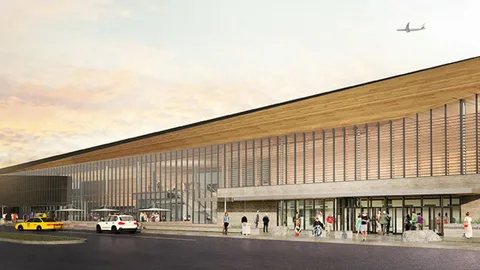 limo service orangeville-Modern airport terminal with glass facade and wooden roof under a sunset sky. People and cars are in the foreground; an airplane flies overhead.