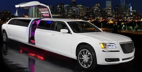 markham limo service-A sleek white limousine with neon interior lighting is parked at night. Its door is open, revealing vibrant colors, against a city skyline backdrop.