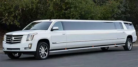 oakville airport limo service-A sleek, white stretch SUV limousine is parked on a road. It features tinted windows and shiny chrome wheels, with lush green trees in the background.