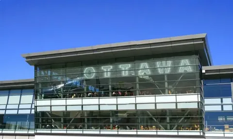 ottawa limo service-Modern glass building with large reflective windows displaying the word "Ottawa" in bold, set against a clear blue sky, conveying a sense of urban sophistication.
