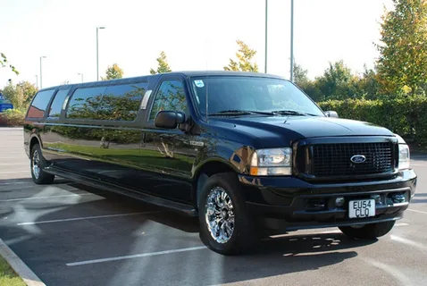 ottawa limo service-A sleek black stretch limousine parked on a sunny day, surrounded by greenery. The vehicle's shiny surface reflects the clear blue sky, exuding luxury.
