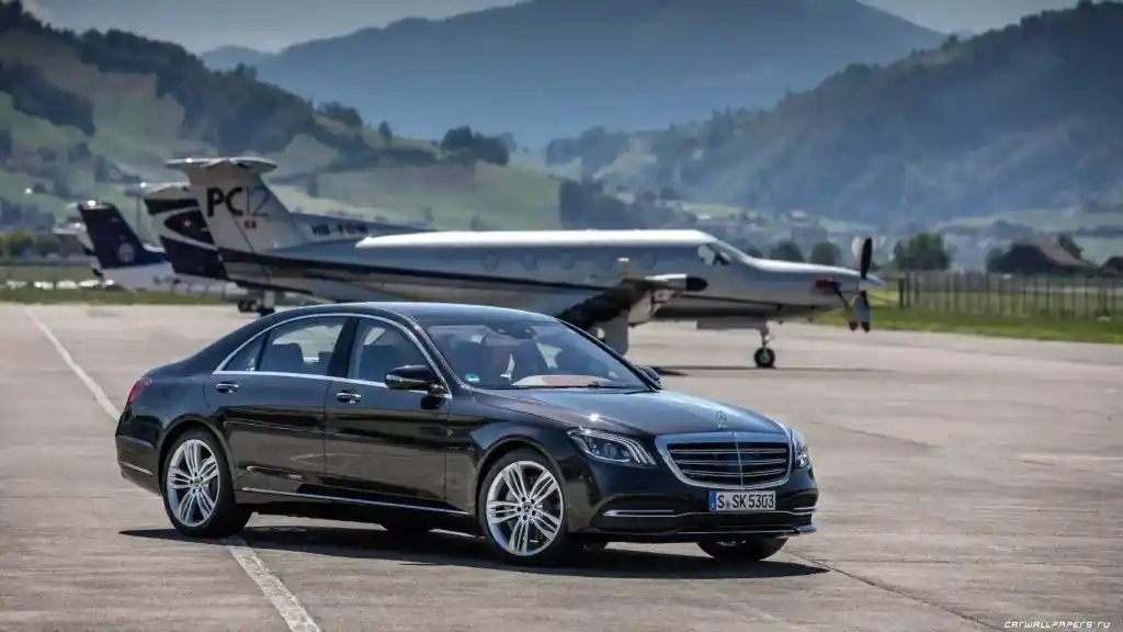 Black Mercedes-Benz positioned near the airport entrance for premium airport transfer service.