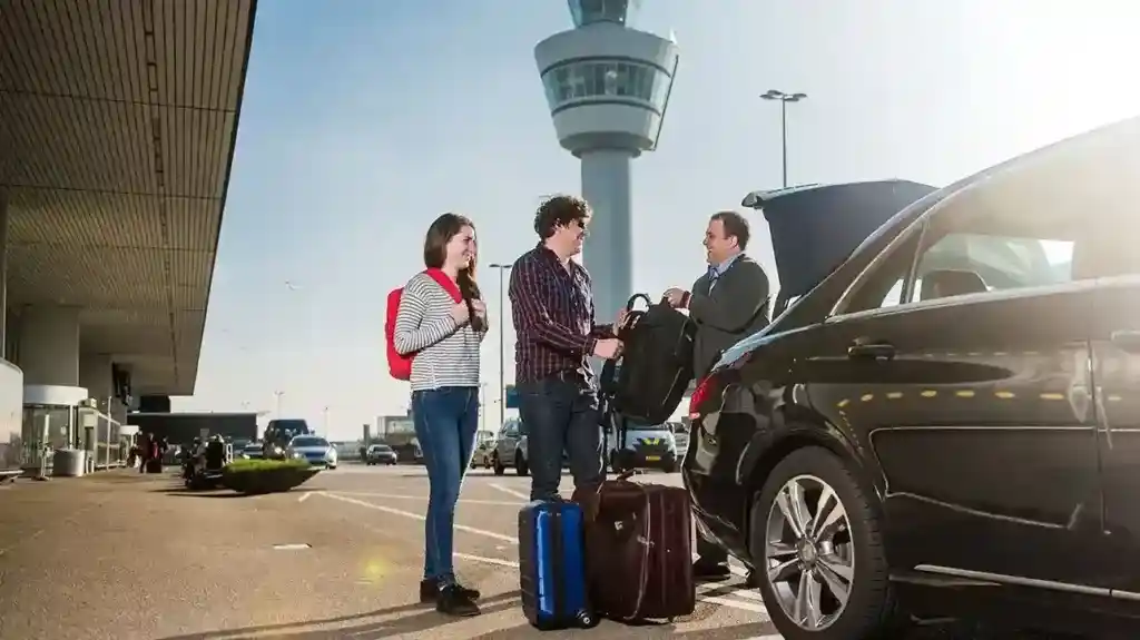 A chauffeur dressed in formal attire opening the door of a sleek black limousine to welcome a passenger.