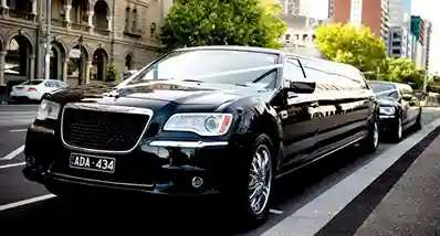 toronto airport limo-A sleek, white stretch limousine parked on a well-lit driveway at night, surrounded by palm trees and a luxurious house, exuding elegance and sophistication.